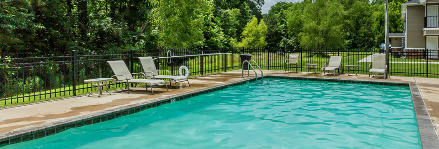 Rectangular swimming pool with multiple reclining chairs around the perimeter.
