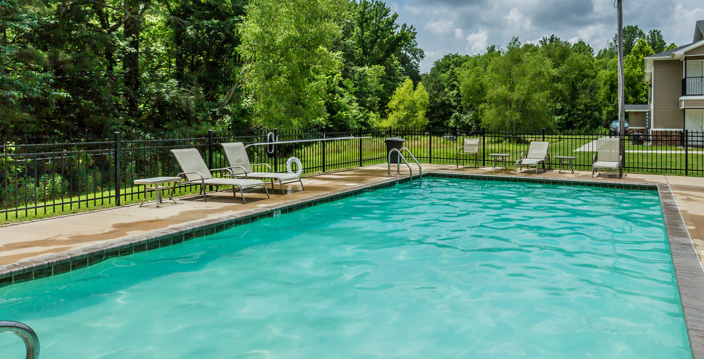 Rectangular swimming pool with multiple reclining chairs around the perimeter