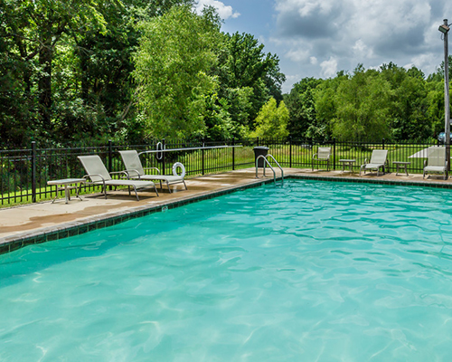 Rectangular swimming pool with multiple reclining chairs around the perimeter